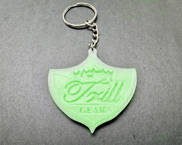 3D-printed TRILL GEAR shield key ring glowing in the dark